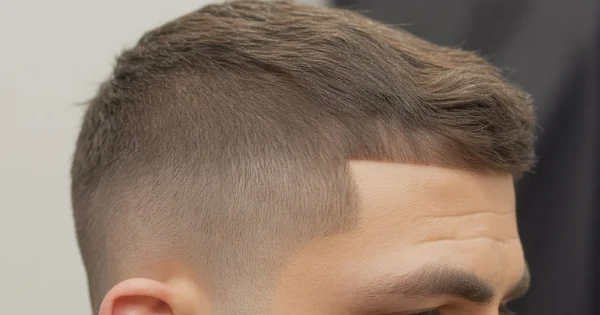 Man with a grown out buzz cut fade haircut featuring a short textured top and clean low fade on the sides.